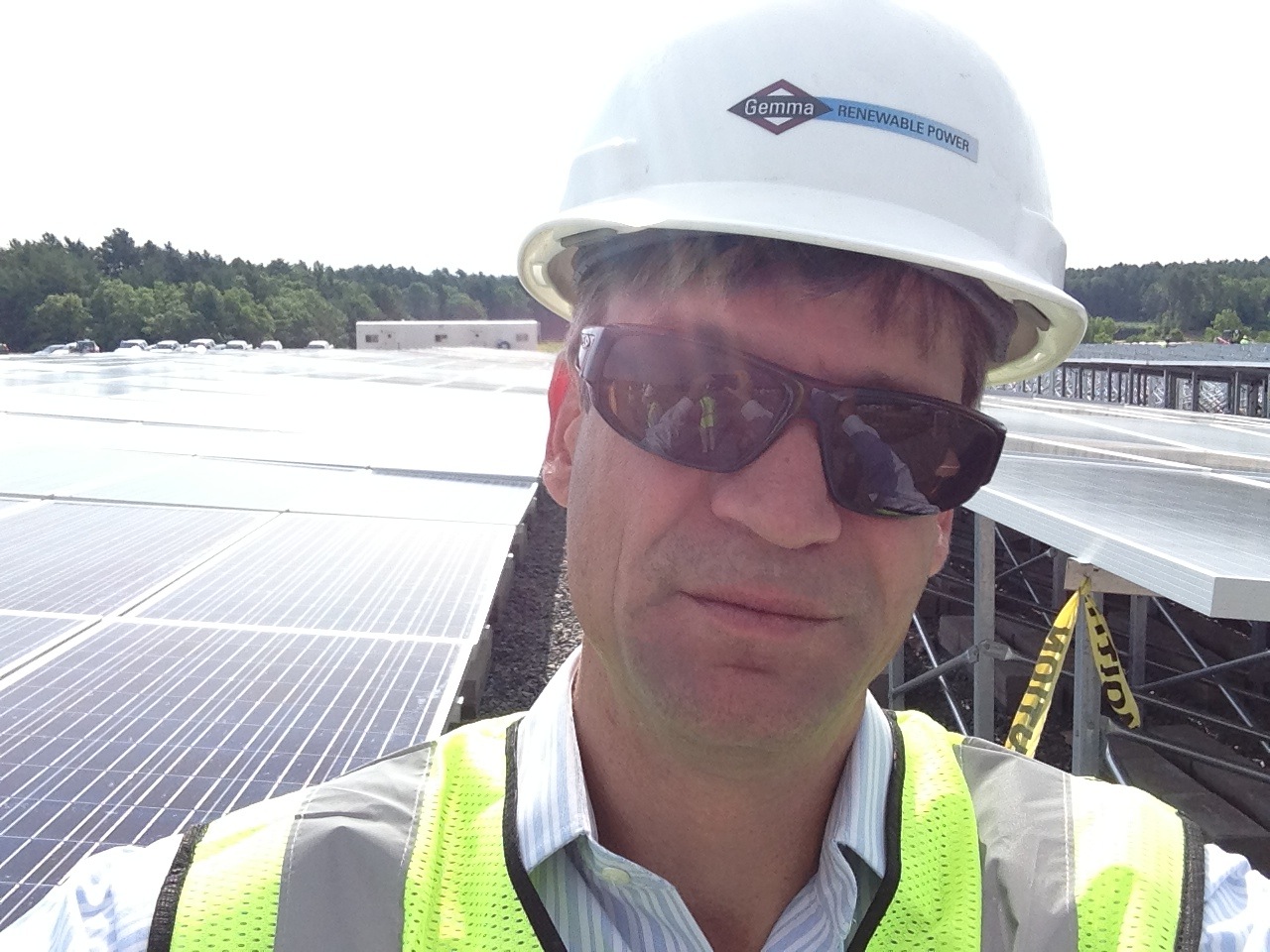 Man in safety gear with solar panels in the background.