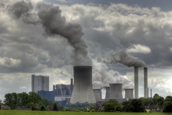 Power plant with smoke and cloudy sky.