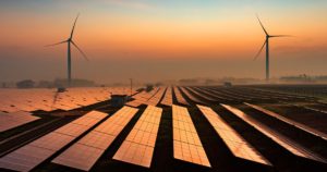 Solar panels and wind turbines at sunset.