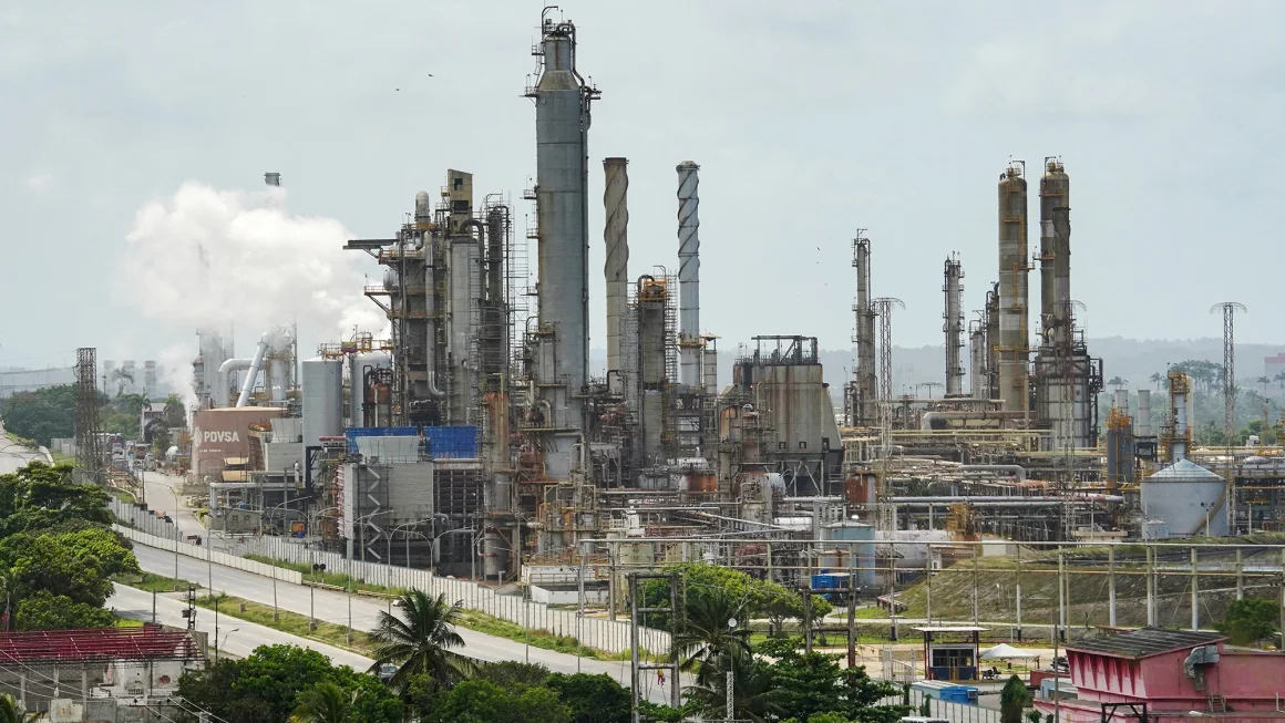 Large industrial refinery with tall towers and pipes under a cloudy sky.