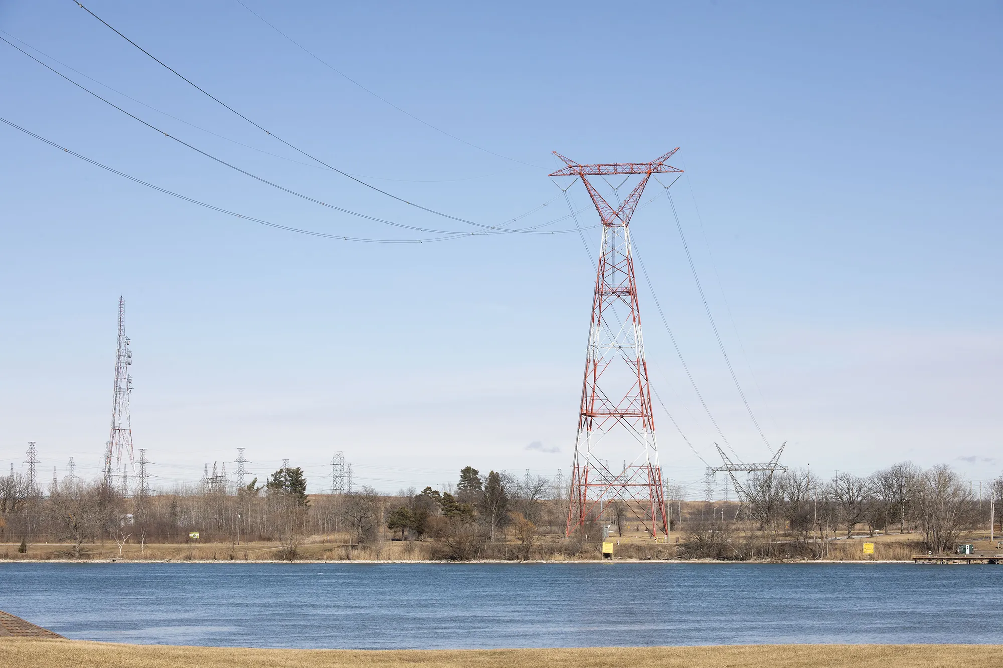 Tall electrical tower near a river on a clear day.